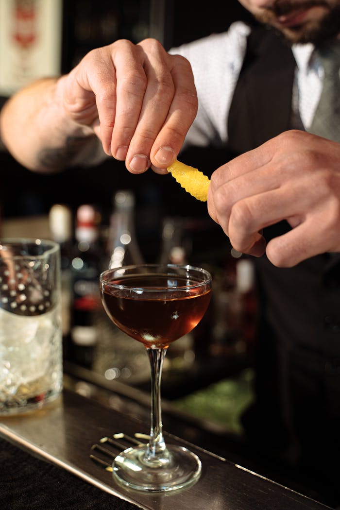 A skilled bartender preparing a classic cocktail with a fresh lemon twist garnish.